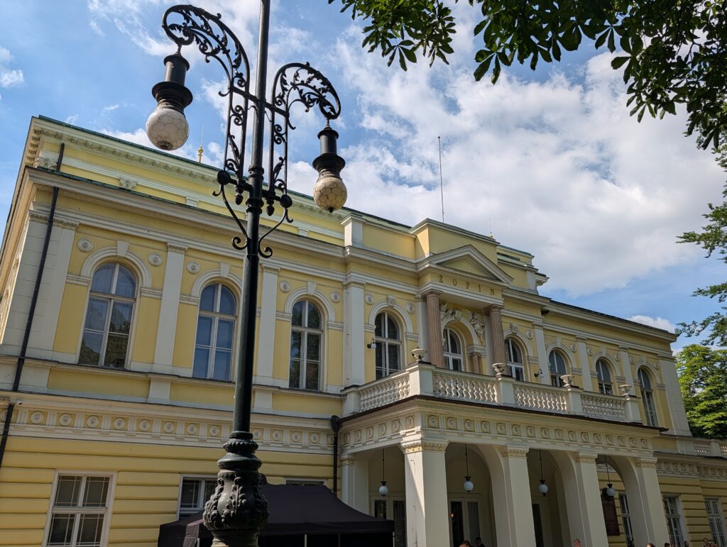 Gelbes Žofín-Palais in Prag mit Rundbogenfenstern und verzierter Straßenlaterne