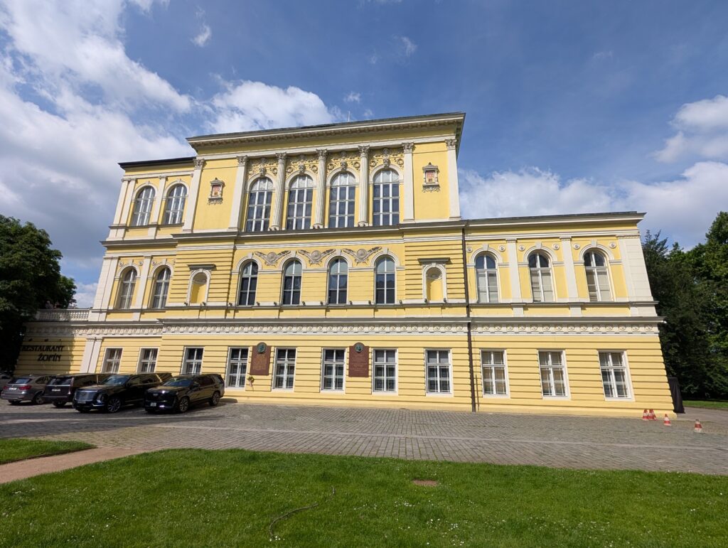 Gelbe Fassade des Žofín-Palais in Prag mit Rundbogenfenstern und Rasenfläche