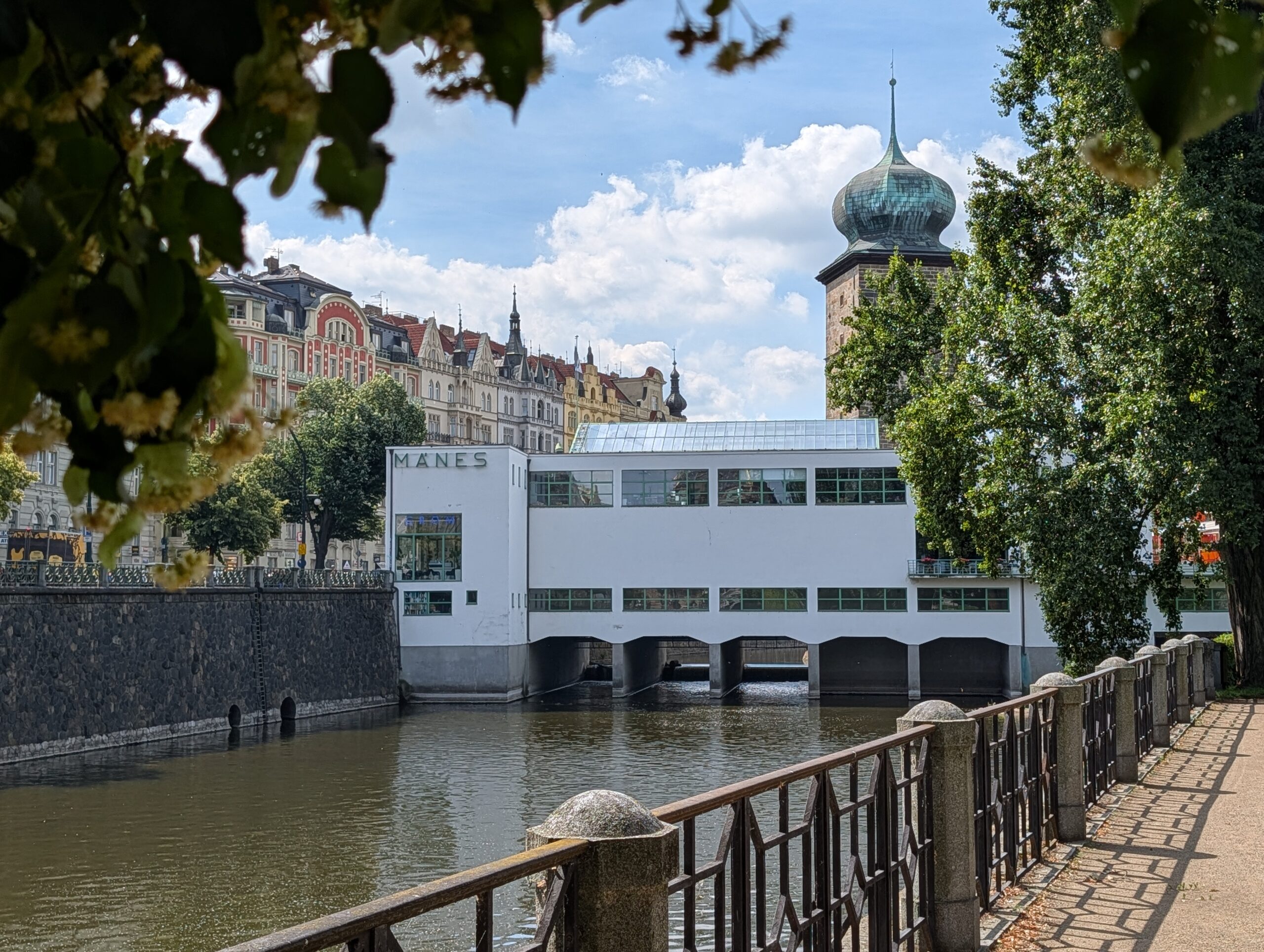 Weiße Mánes-Ausstellungshalle über der Moldau mit Šítkov-Wasserturm im Hintergrund