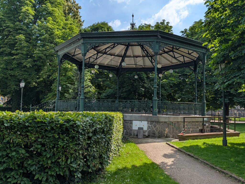 Historischer Musikpavillon aus Metall zwischen Hecken und Bäumen auf der Slawischen Insel in Prag