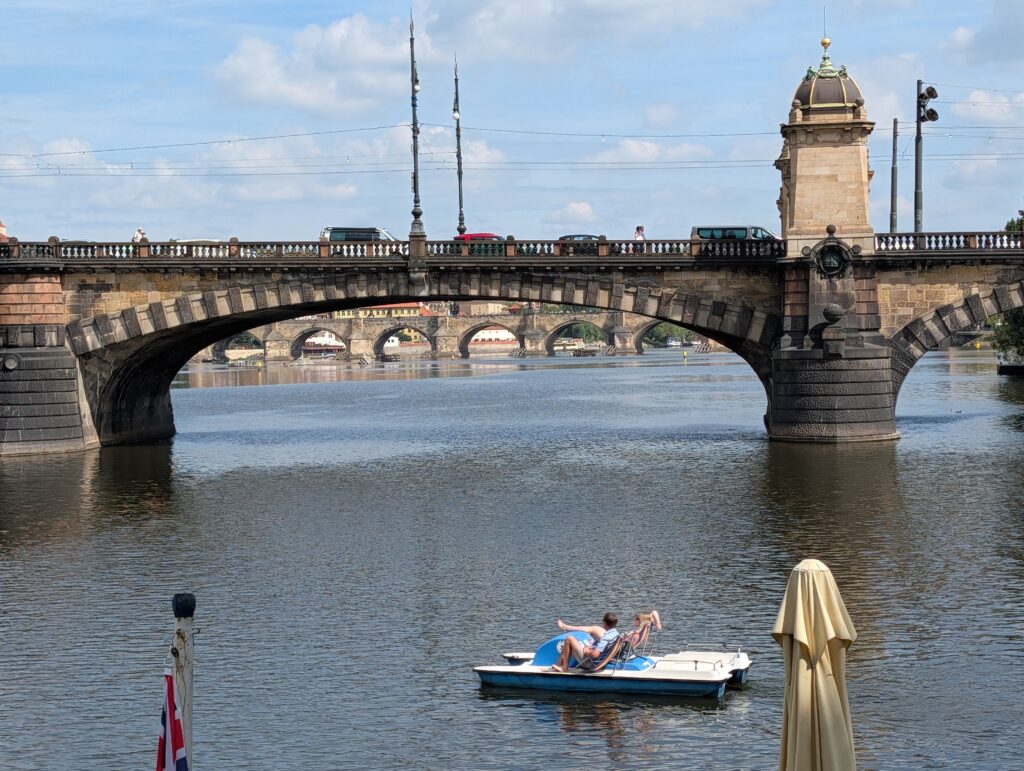 Blau-weißes Tretboot auf der Moldau vor der Brücke der Legionen in Prag