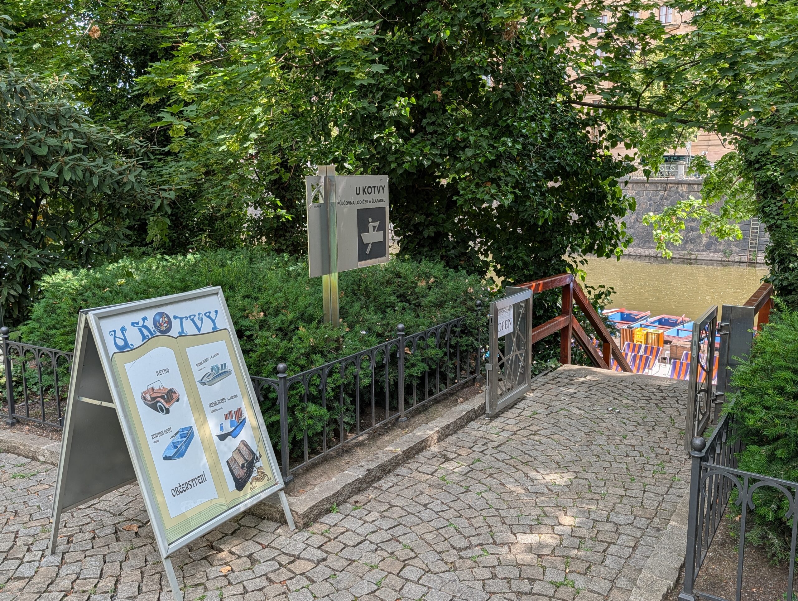 Zugang zum Bootsverleih U Kotvy mit Hinweisschildern und Tretbooten auf der Slawischen Insel in Prag