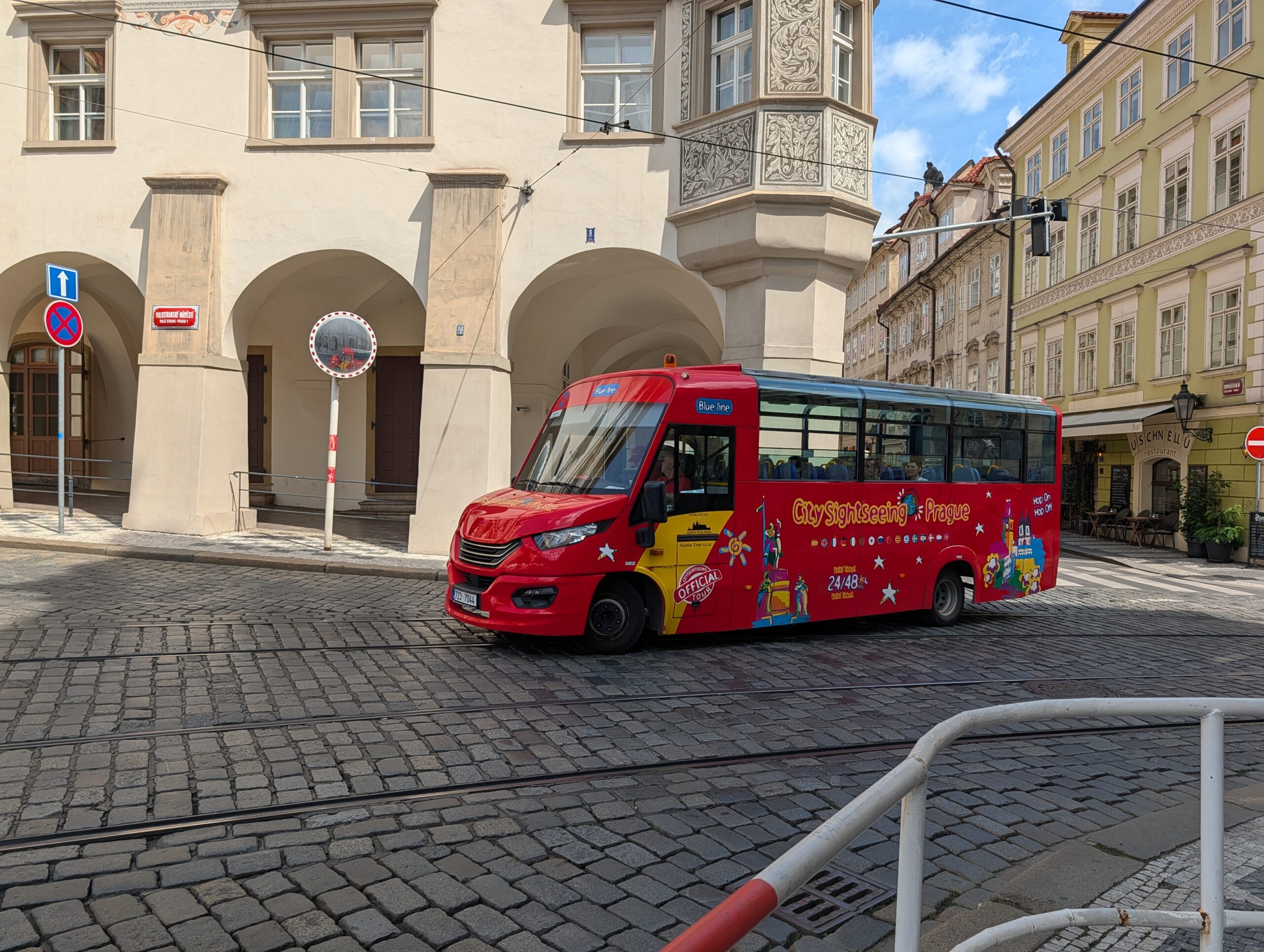 Roter City-Sightseeing-Bus auf einer gepflasterten Straße zwischen historischen Häusern in Prag