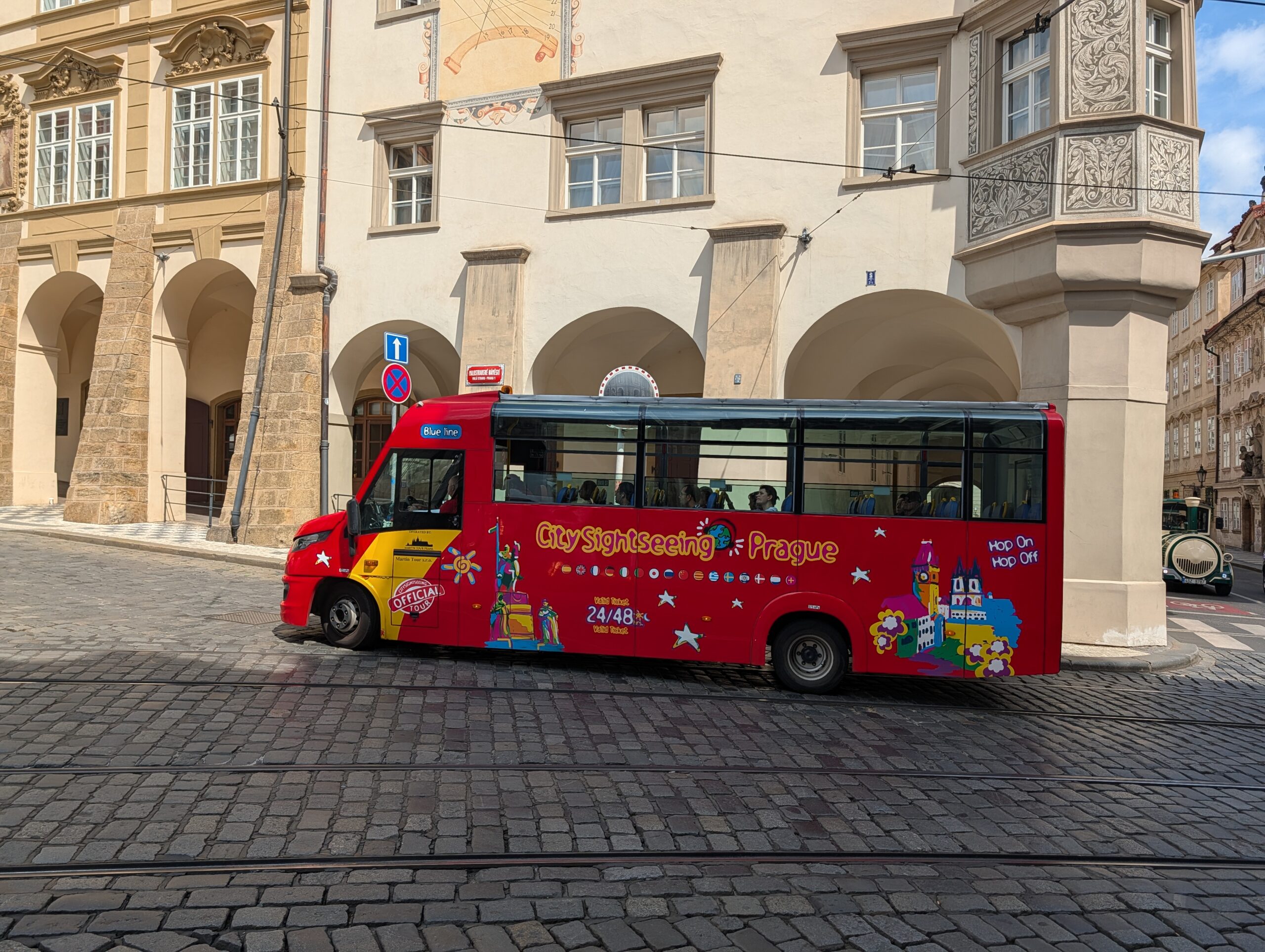 Roter City-Sightseeing-Bus vor historischen Gebäuden mit Arkaden in der Prager Altstadt