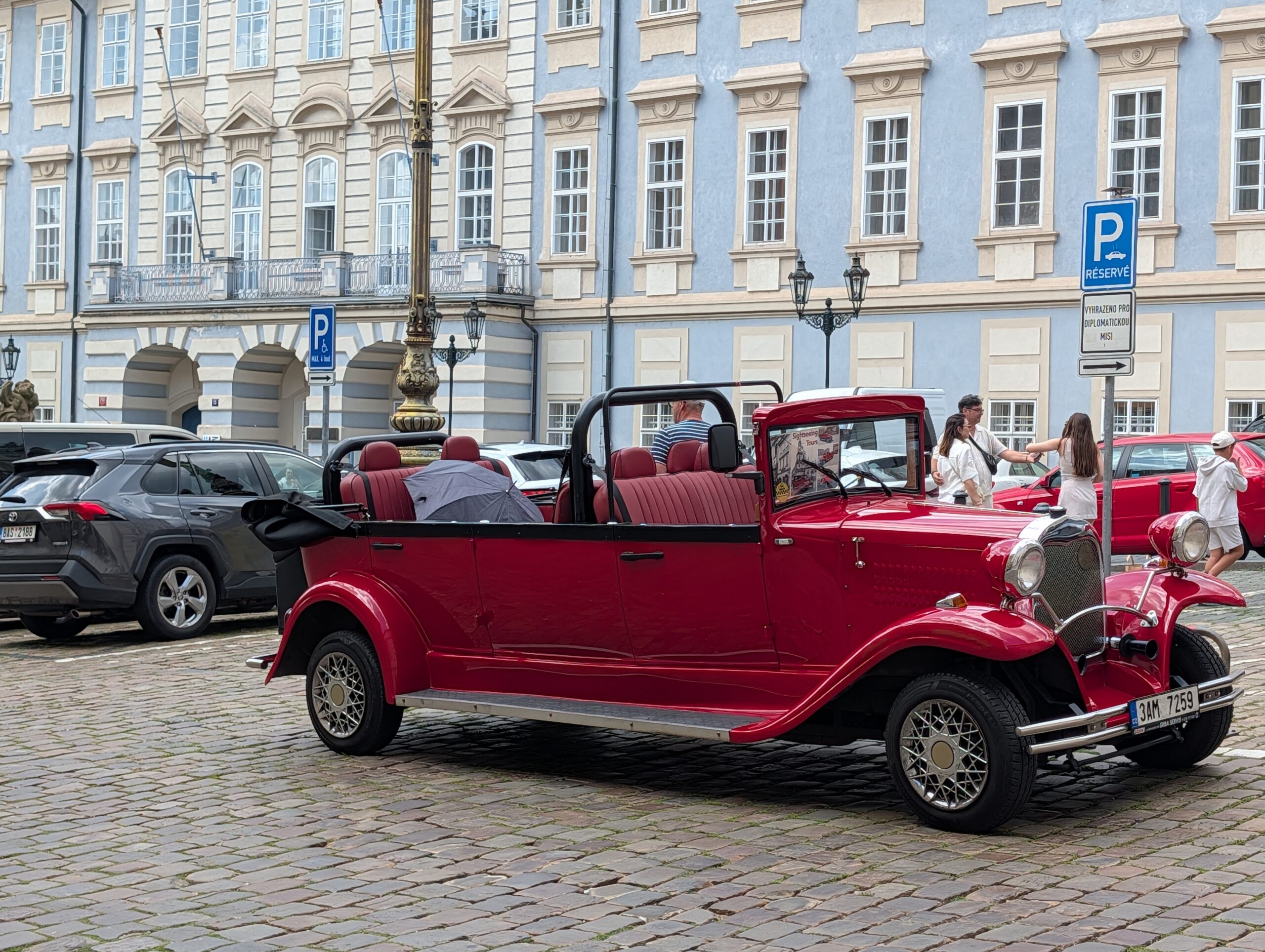 Roter offener Oldtimer auf Kopfsteinpflaster vor historischen Gebäuden in Prag