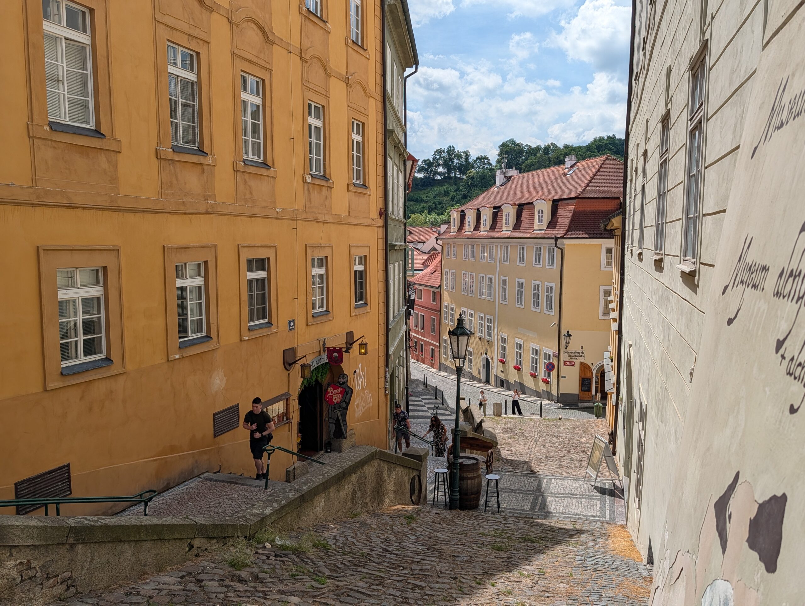 Steile gepflasterte Gasse beim Alchemistenmuseum in Prag mit historischen Häusern und Blick zur Kleinseite
