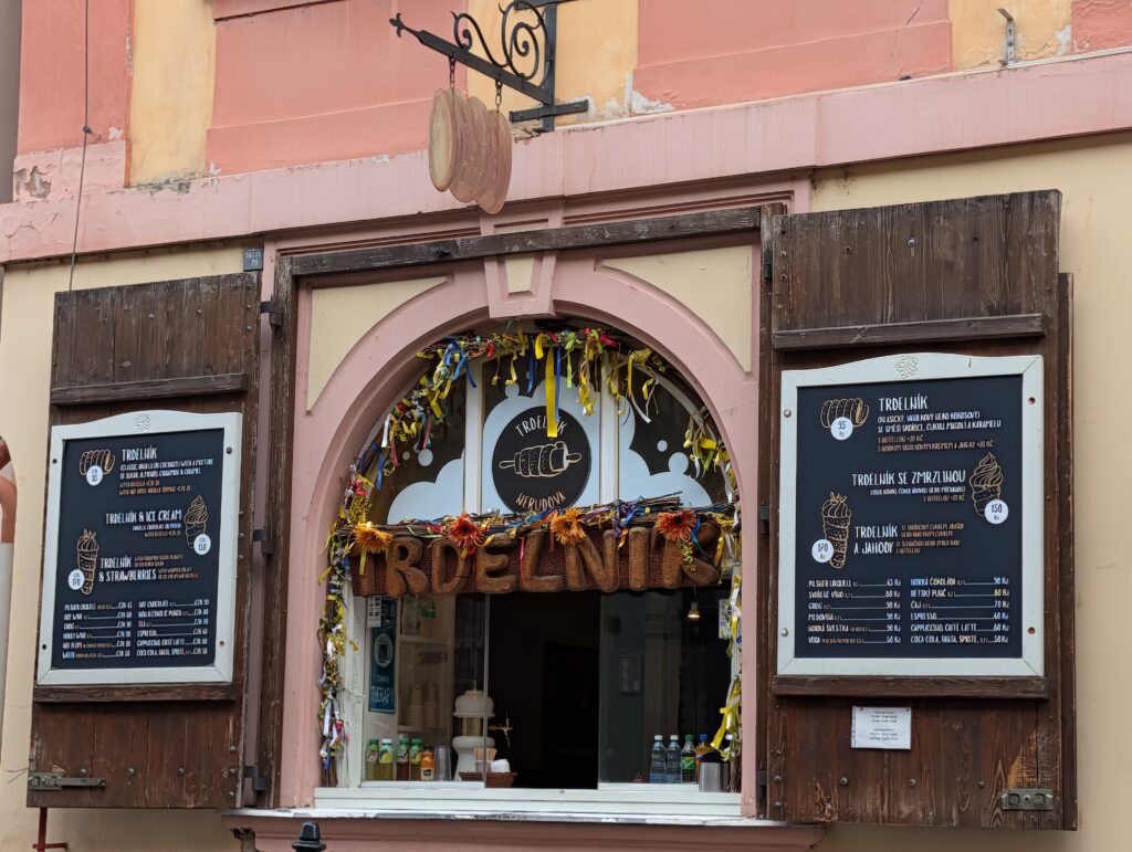 Verkaufsfenster eines Trdelník-Stands mit Speisekarten auf der Prager Kleinseite in Prag