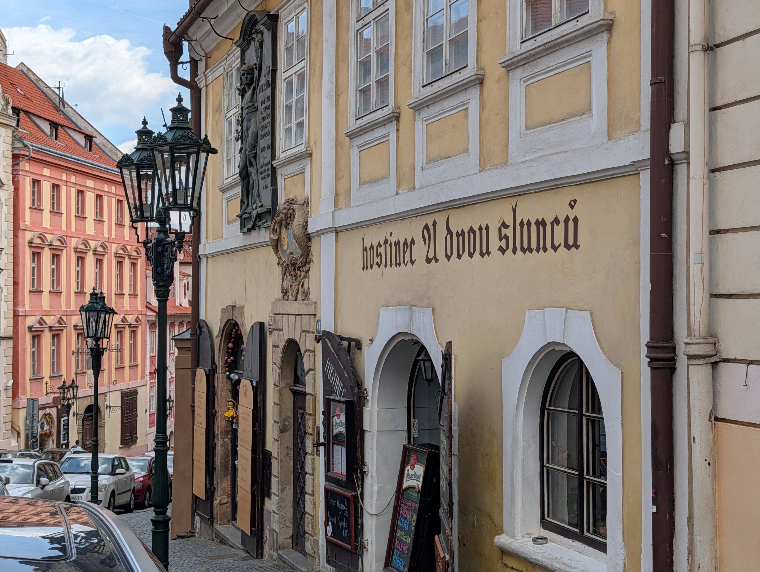 Fassade des Gasthauses Zu den zwei Sonnen mit historischem Schriftzug auf der Prager Kleinseite