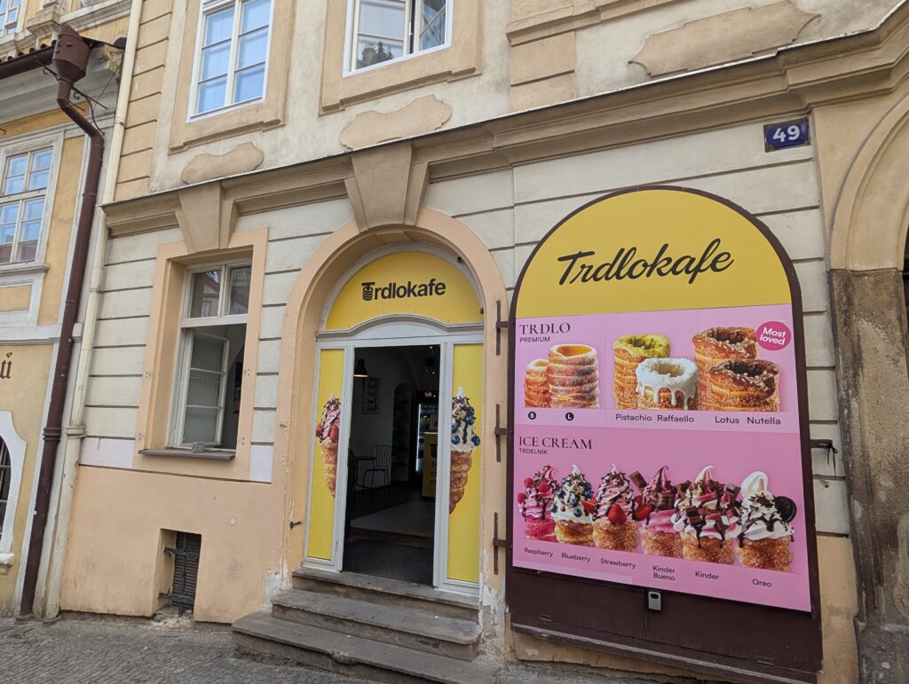 Eingang zum Trdlokafe mit großer Angebotstafel für Trdelník und Eis in Prag