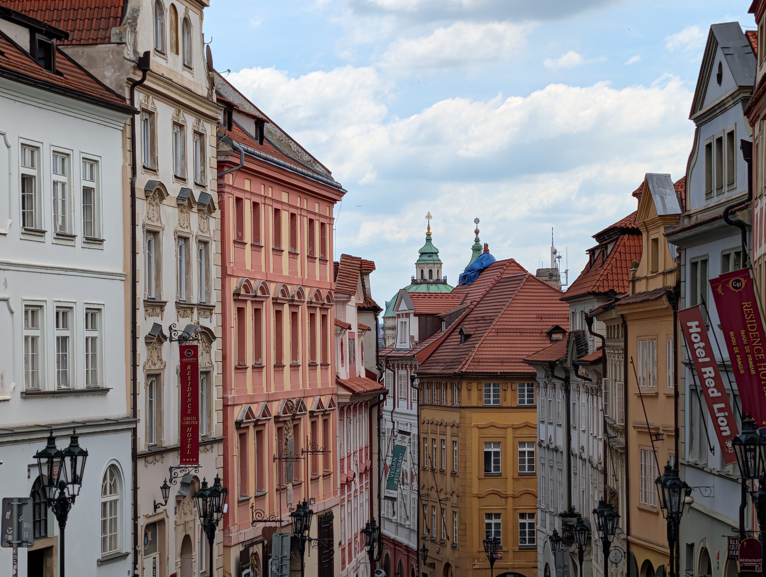 Blick durch die Nerudagasse mit farbigen historischen Häusern und Kirchtürmen auf der Prager Kleinseite