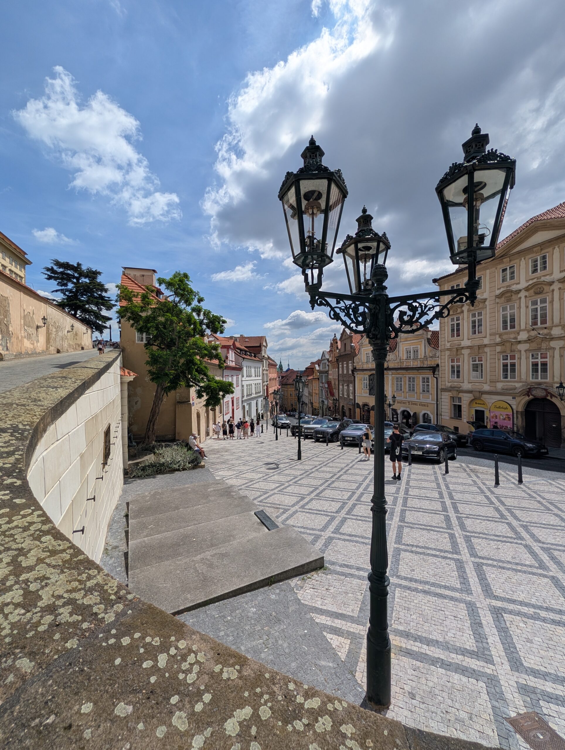 Straße Ke Hradu mit gemustertem Pflaster, historischen Häusern und verzierten Laternen in Prag