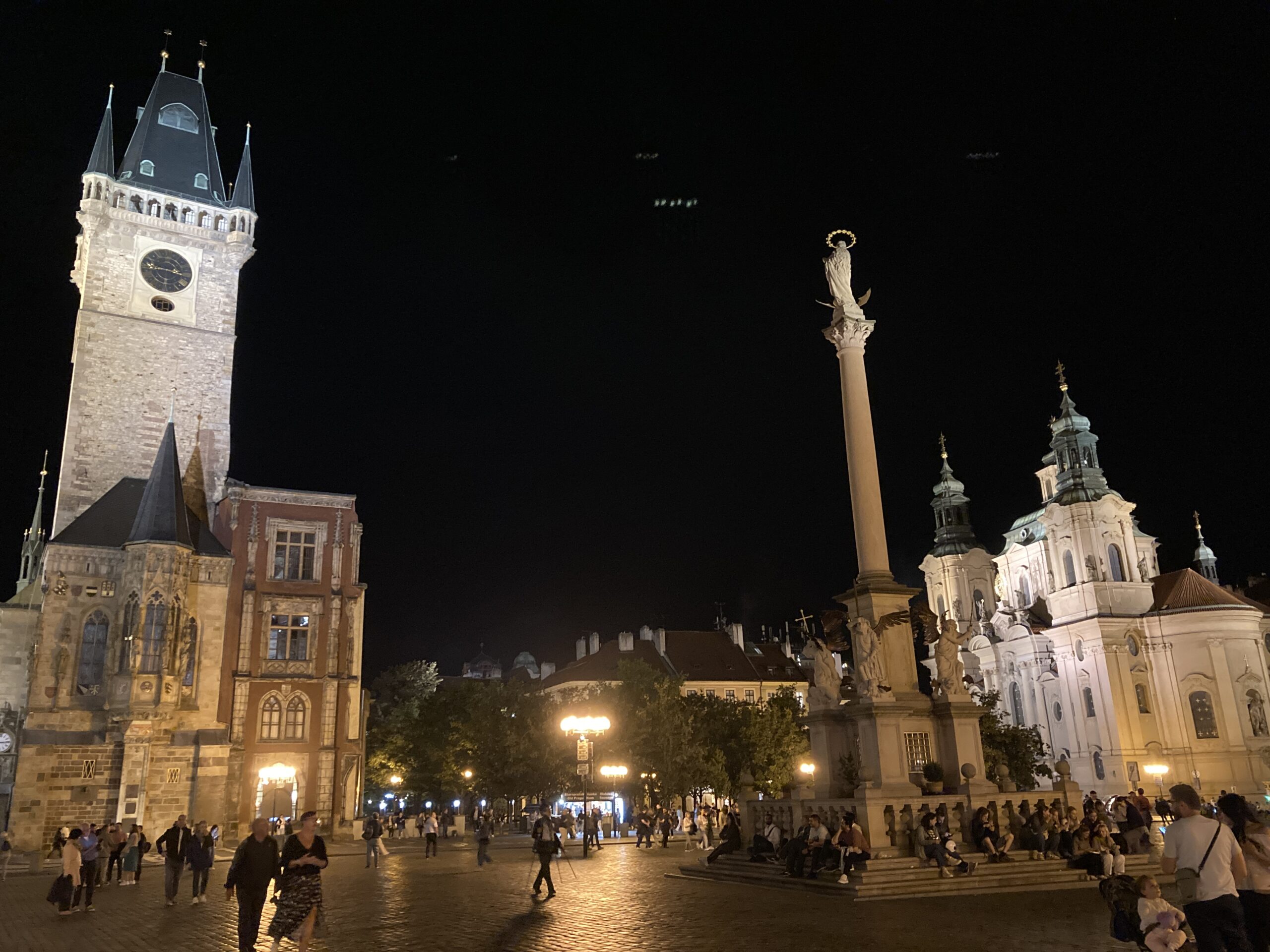 Altstädter Ring in Prag bei Nacht mit Altstädter Rathaus, Mariensäule, St.-Nikolaus-Kirche und zahlreichen Besuchern.