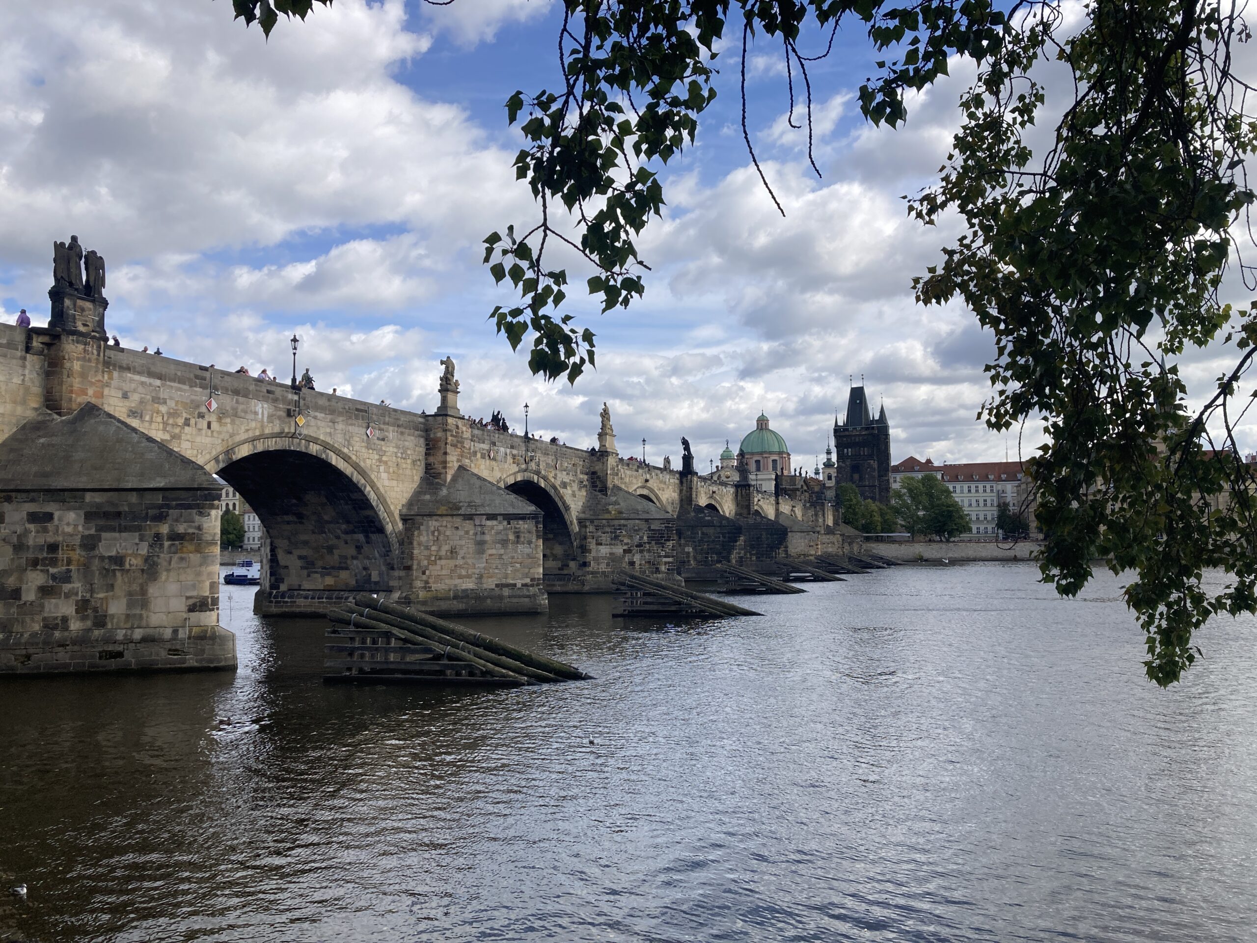 Karlsbrücke mit Steinbögen und Skulpturen über der Moldau sowie Altstädter Brückenturm im Hintergrund.