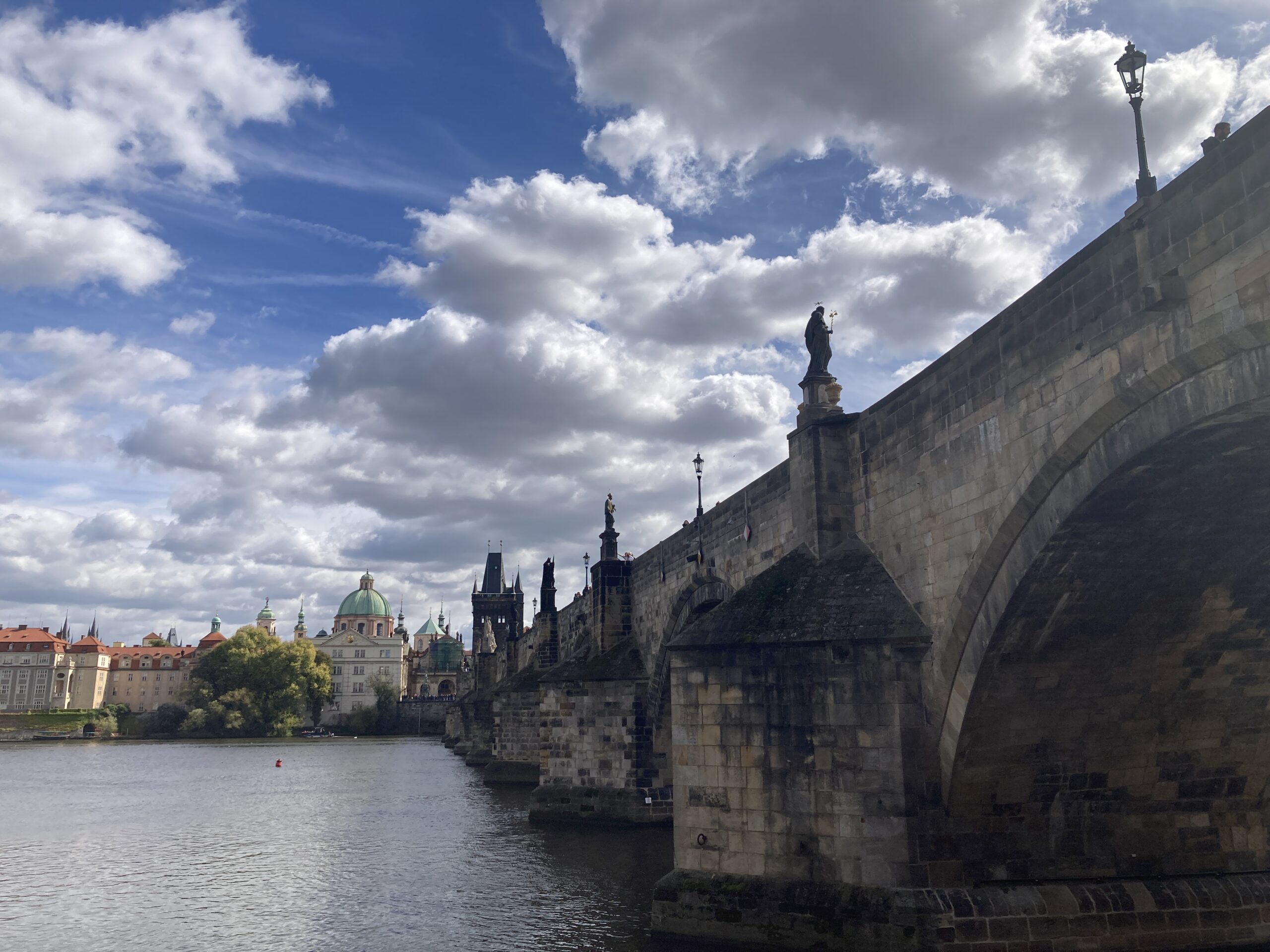 Karlsbrücke mit Steinbögen und Skulpturen über der Moldau sowie Altstädter Brückenturm im Hintergrund.