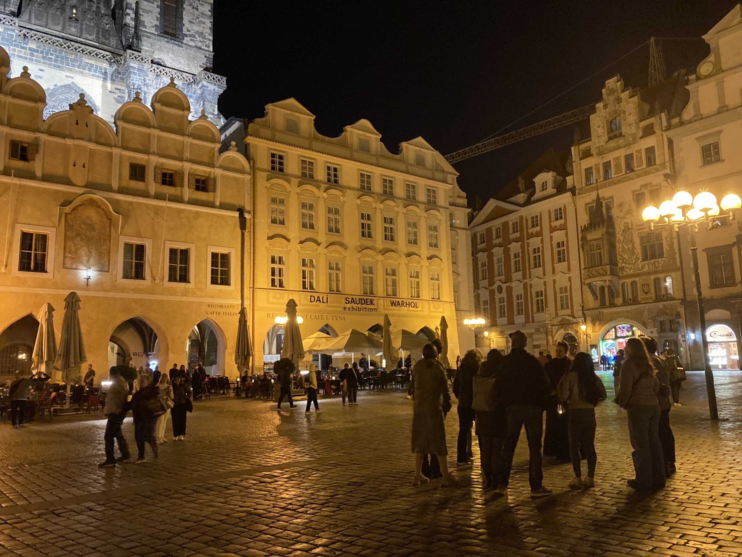 Historische beleuchtete Häuser am Altstädter Ring in Prag mit Besuchern auf dem nächtlichen Platz.