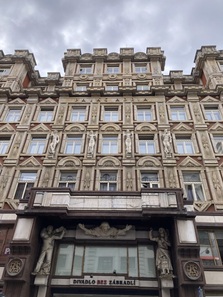 Verzierte Fassade des Adria-Palasts am Jungmannplatz in Prag mit Figuren und Schriftzug Palác Adria.