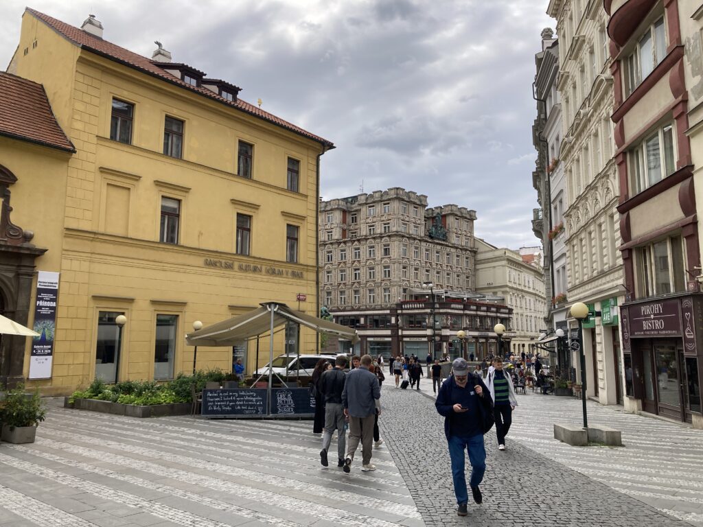 Jungmannplatz in Prag mit historischen Häusern, Fußgängern und gepflasterter Fußgängerzone.